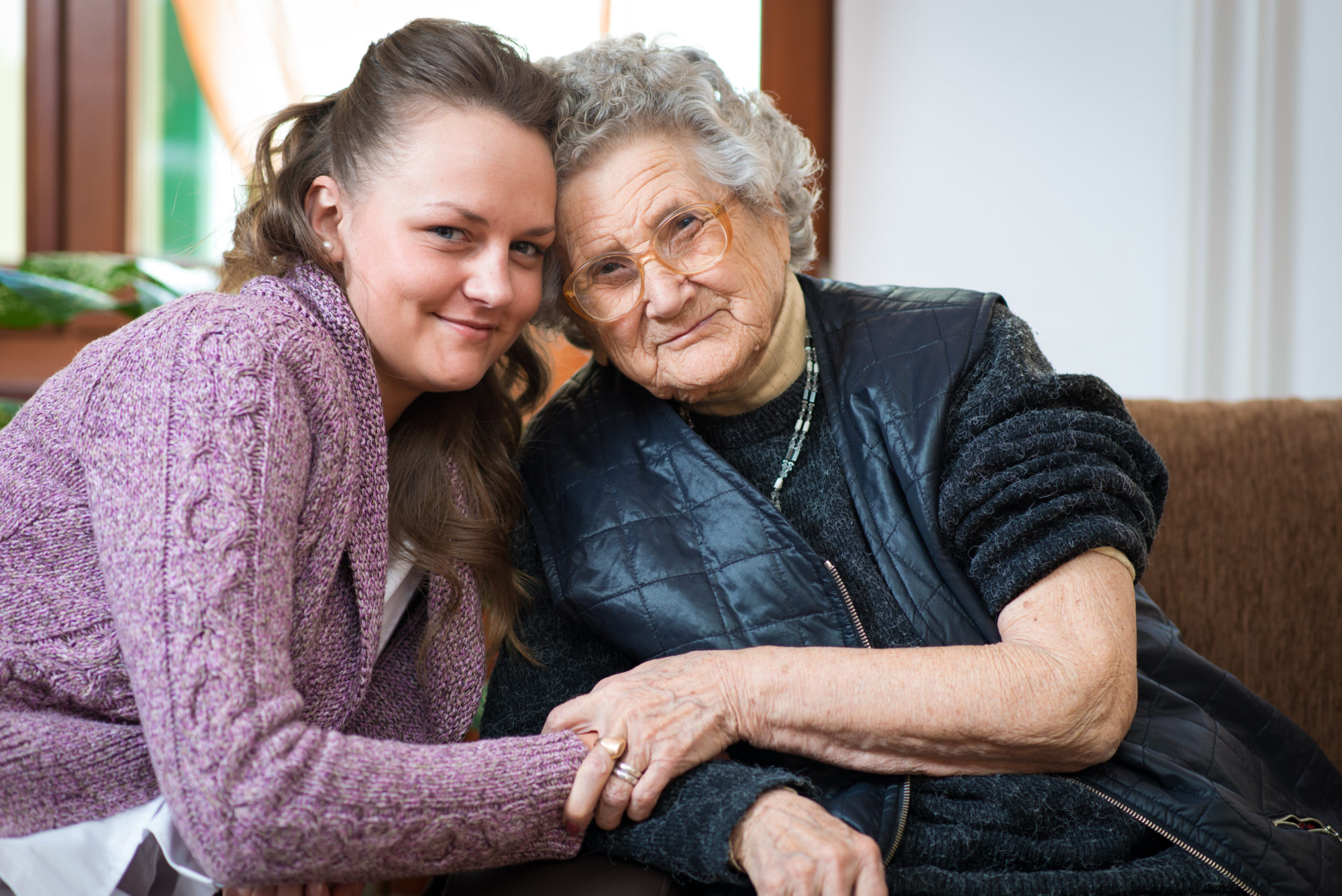 Eldre dame får besøk av frivillig Foto: Adobe Stock