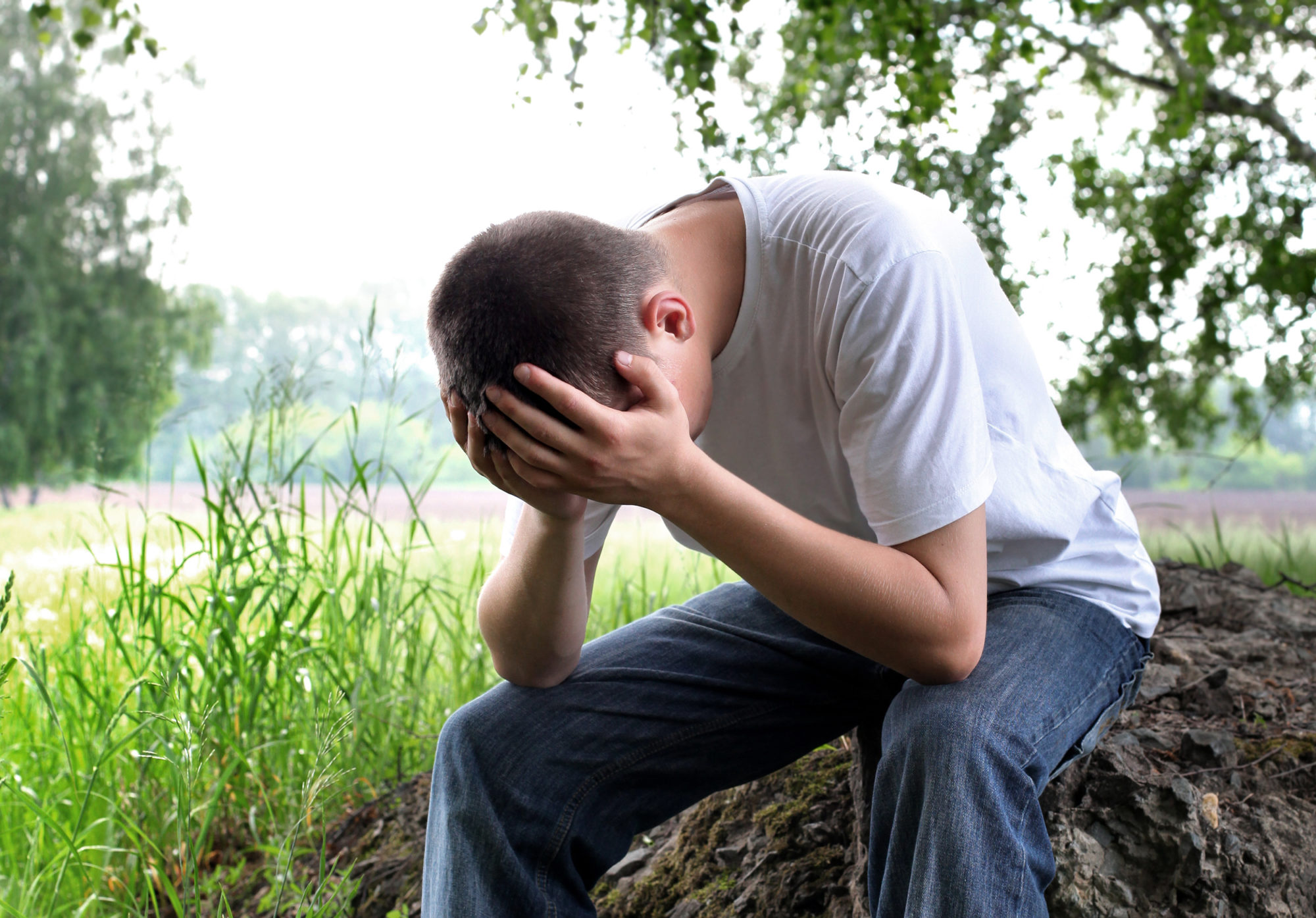 Sorrowful Young Man sit on the Nature Background