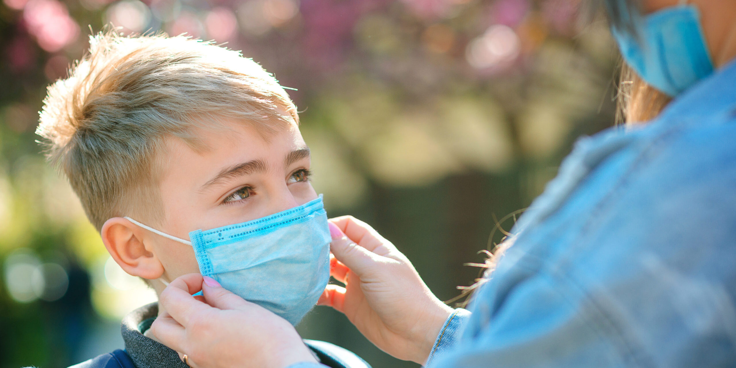 Mother puts her son a face protective mask outdoors. Coronavirus, illness, infection, quarantine, medical mask, COVID-19.